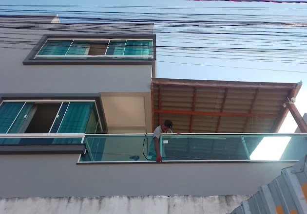 Instalação de guarda-corpo de vidro verde em sacada de sobrado
